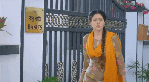 a woman is standing in front of a fence with a sign that says basu 's