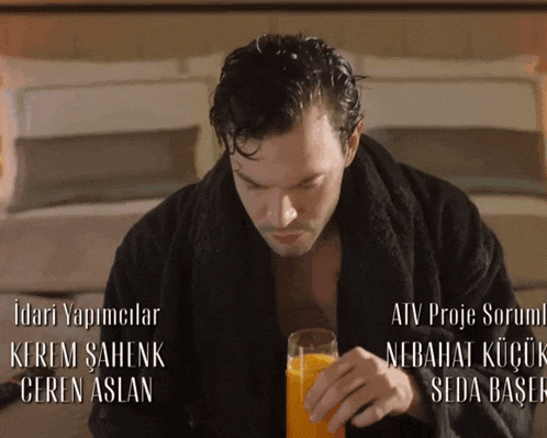 a man in a black robe is holding a glass of orange juice in front of a sign that says " atv proje sorumlu "