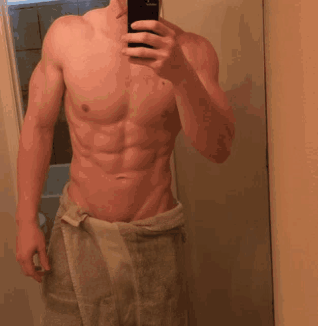 a shirtless man is taking a selfie with his phone