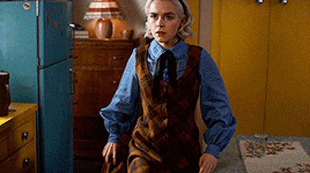 a woman in a plaid dress is sitting at a table in a room .