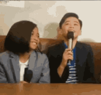 a boy and a girl are sitting next to each other on a couch . the boy is holding a microphone .