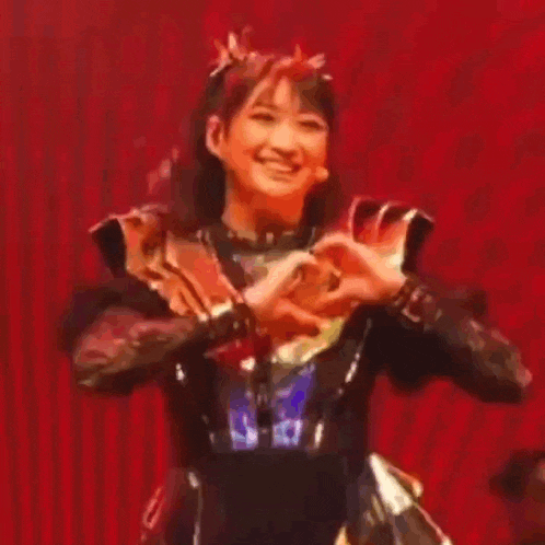 a woman is making a heart shape with her hands while smiling .