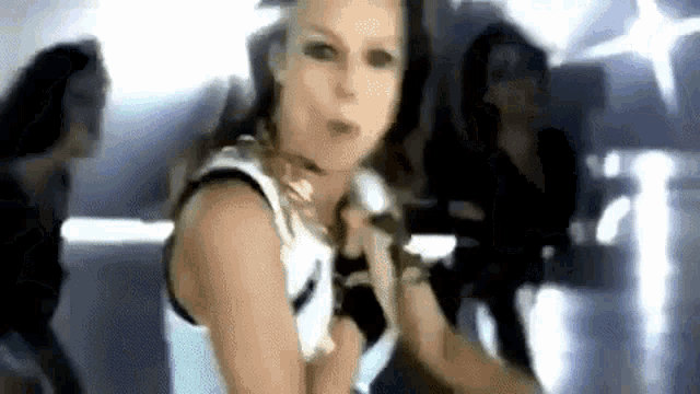 a woman in a white tank top is singing into a microphone in a video .