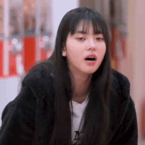a young woman with long black hair and bangs is making a funny face with her mouth open .