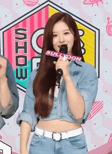 a woman holds a microphone in front of a sign that says sullyoon