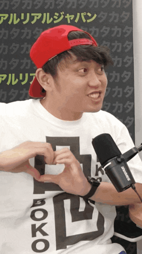 a man wearing a shure microphone is making a heart shape with his hands
