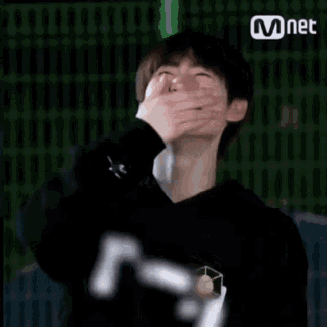 a young man is laughing and clapping his hands while wearing a black shirt .