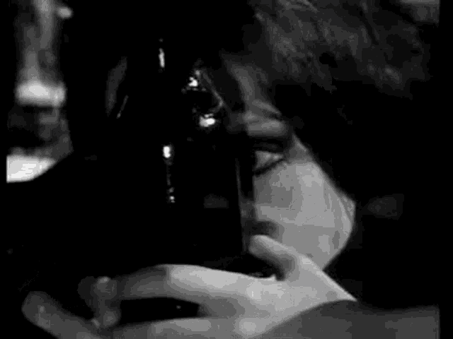 a black and white photo of a woman smoking a cigarette .