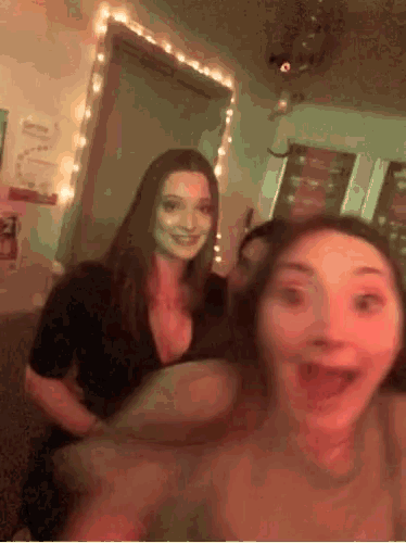 two girls are posing for a picture in a room