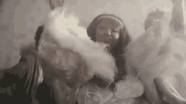 a woman in a white dress is dancing in a room with smoke coming out of her hands .