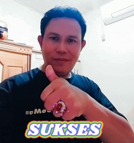 a man with a ring on his finger giving a thumbs up in front of a sign that says sukses