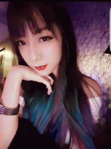 a woman with blue and purple hair is wearing a watch on her wrist