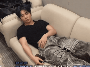 a man is laying on a couch with korean writing on the bottom