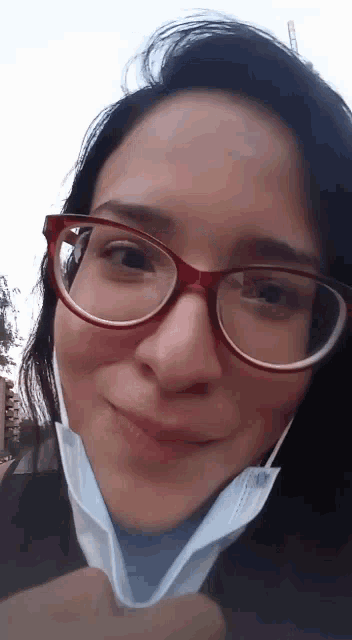 a woman wearing glasses and a mask looks at the camera