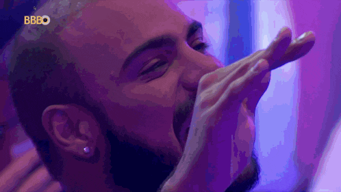 a man with a beard is covering his mouth with his hand and the letters bbbo are visible in the corner