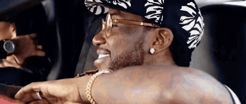 a man wearing a hat and sunglasses is sitting in a car and smiling .