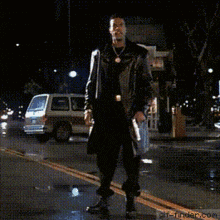 a man in a trench coat is dancing on a street