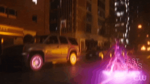 a gmc suv is parked in front of a building with purple lights coming out of it