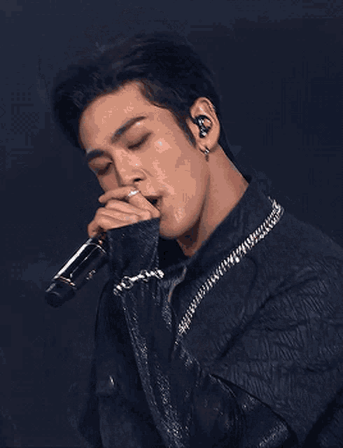 a man in a blue shirt is singing into a microphone .
