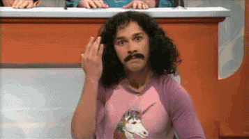 a man with long hair and a mustache is wearing a pink unicorn shirt and giving the middle finger .