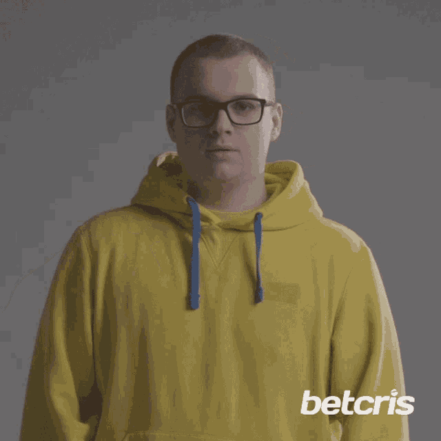 a man wearing glasses and a yellow hoodie has betcris written on the bottom