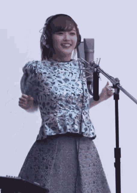 a woman wearing headphones is singing into a microphone in a studio .