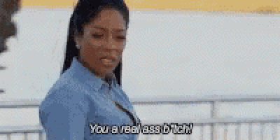 a woman in a blue shirt is standing in front of a body of water and saying `` you are a real ass bitch '' .