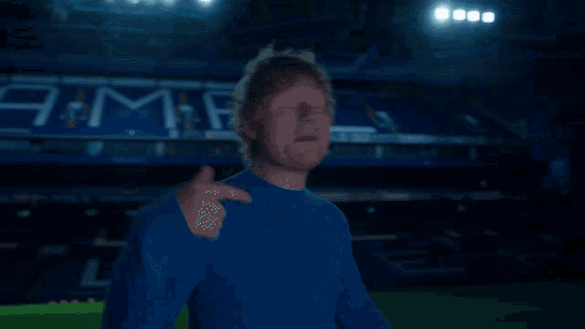 a man in a blue shirt stands in front of a stadium that has the word jama on it