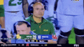 a man wearing headphones is watching a football game on television .