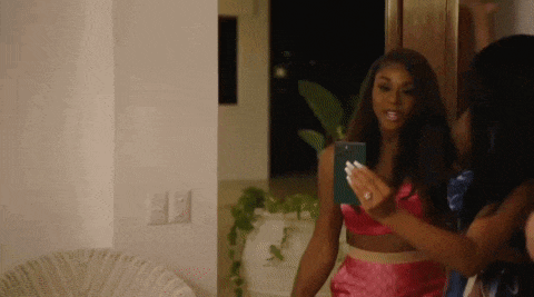 a woman in a pink dress is taking a selfie with her phone .