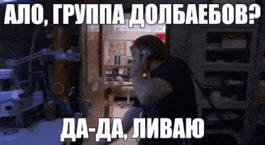 a man is talking on a cell phone in a dark room with russian writing on it