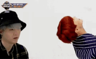 a man in a hat is standing next to another man with a red head .