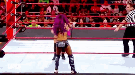a woman is standing in a wrestling ring with a referee .