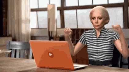a woman in a striped shirt is sitting in front of a laptop