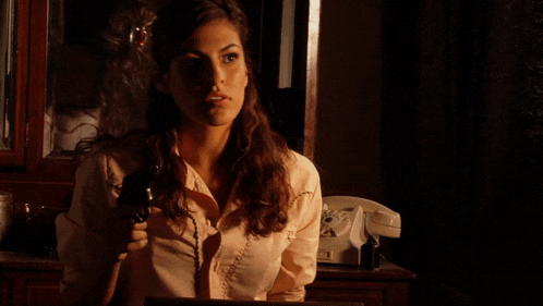 a woman sitting in a dark room with a telephone in the background