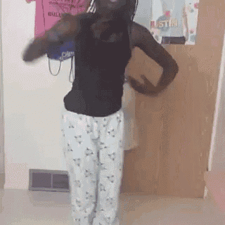 a woman wearing pajama pants and a black tank top dancing