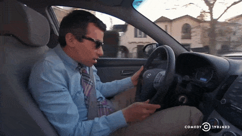 a man driving a car with a comedy central logo on the dash