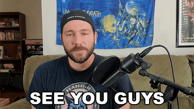 a man sitting in front of a microphone with the words see you guys
