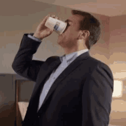 a man in a suit is drinking out of a plastic cup .