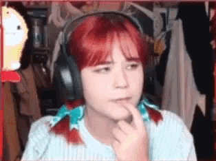 a girl with red hair and headphones is making a funny face .