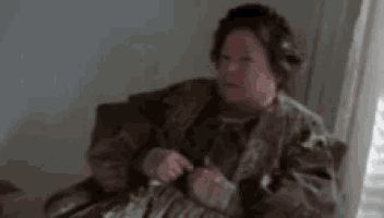 an elderly woman is sitting in a chair in a dark room .