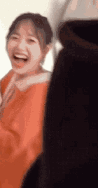 a woman in a red dress is laughing while standing next to a man in a black jacket .