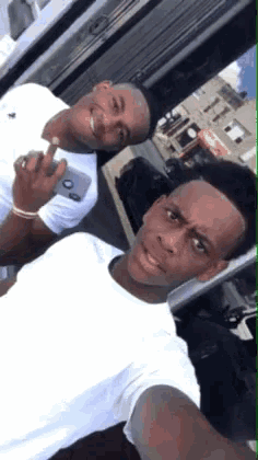 two young men are posing for a picture and one is holding a phone that says ' abercrombie & fitch ' on it