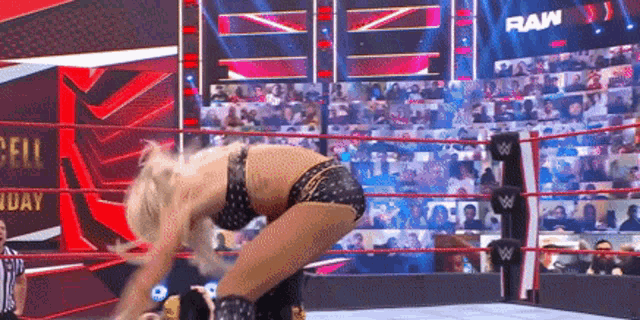 a woman is bending over in a wrestling ring while a referee watches .