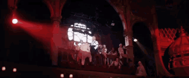 a group of people are standing in a dark room in front of a window .