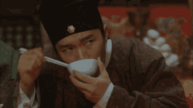 a man wearing a black hat is eating from a bowl