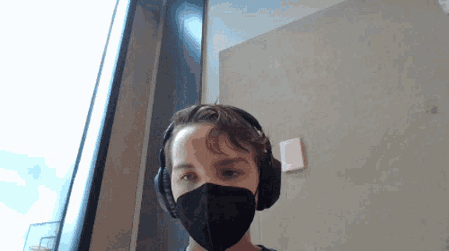 a man wearing headphones and a face mask looks at the camera