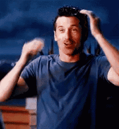 a man in a blue shirt is holding his hair in his hands