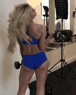 a woman in a blue bikini is holding a dumbbell in her hand