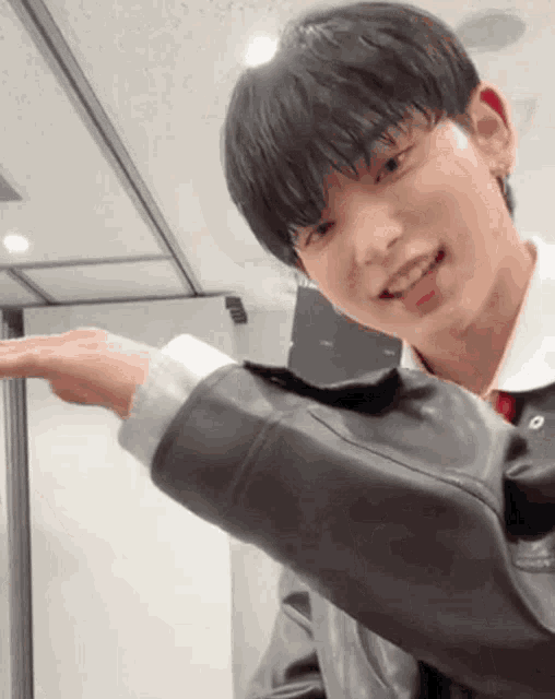 a young man wearing a leather jacket is smiling and pointing at something